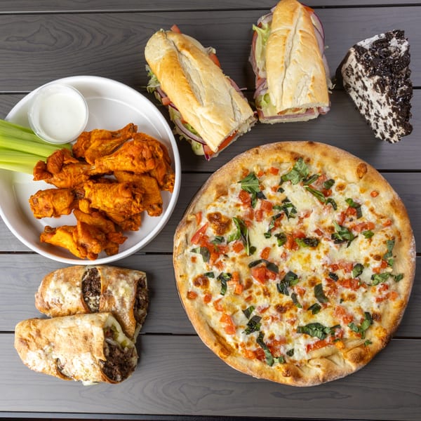 Annie's Pizza Subs & Wings spread: pizza, subs, wings, calzones, and cookies and cream cake.